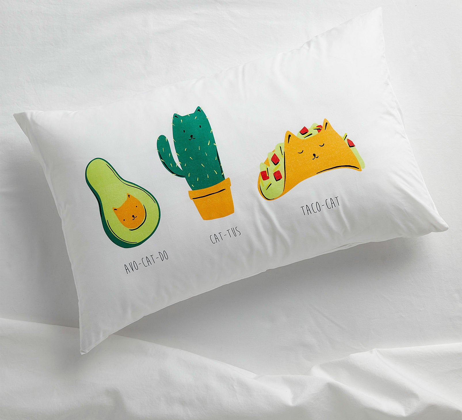 A pillowcase with three illustrations of a cat as an avocado, cactus and taco