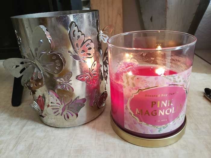 A lit candle sitting on a desk. Half of the wax is gone, indicating that it's already been burning.