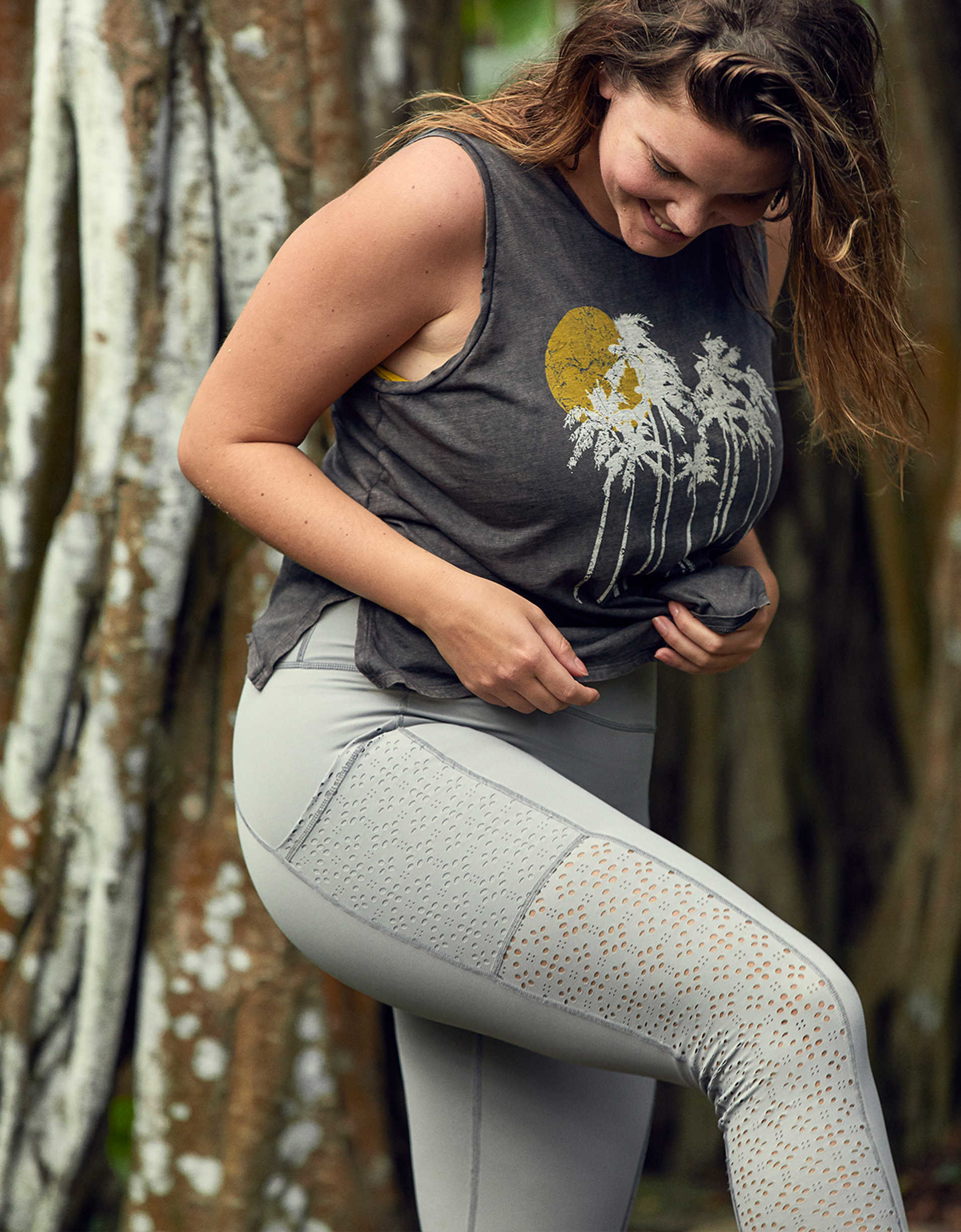 Model wearing leggings outside showing the side with a pocket and laser-cut pattern from the hip down to the ankle