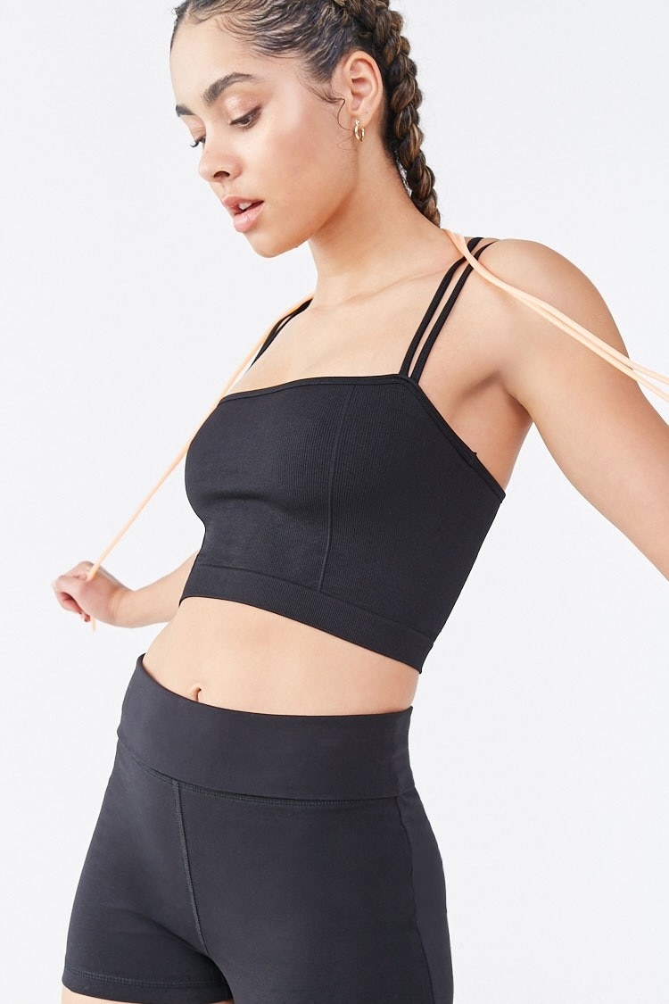 Model wearing black sports bra with jump rope across her shoulders