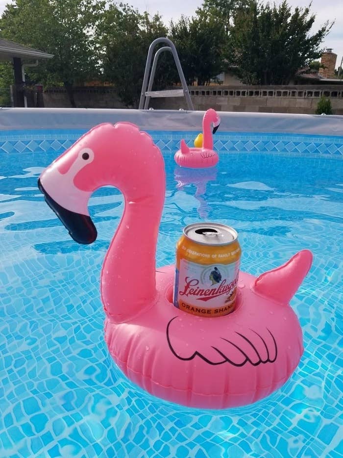 An inflatable flamingo in holding a drink can in a pool