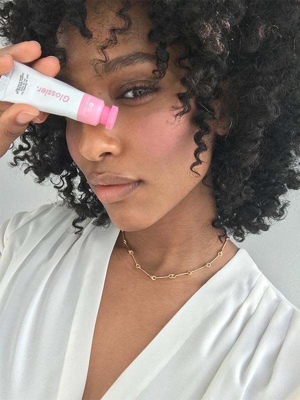 A model holding a tube of the cream blush to her face