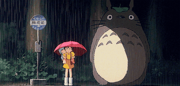 Satsuki, Mei, and Totoro waiting in the rain at a bus stop