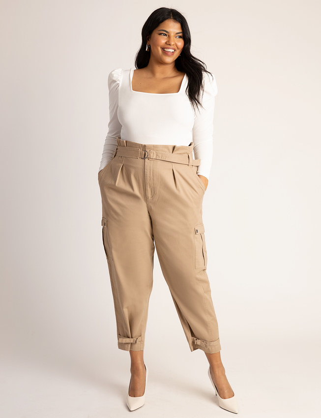Model wearing the pants with heels and a white top 