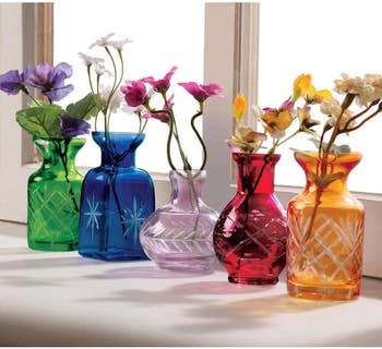 Five small glass vases in different sizes with etching on the bases in green, blue, purples, red, and orange