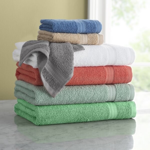 Stack of towels in green, light blue, coral, white, grey, sand, and medium blue