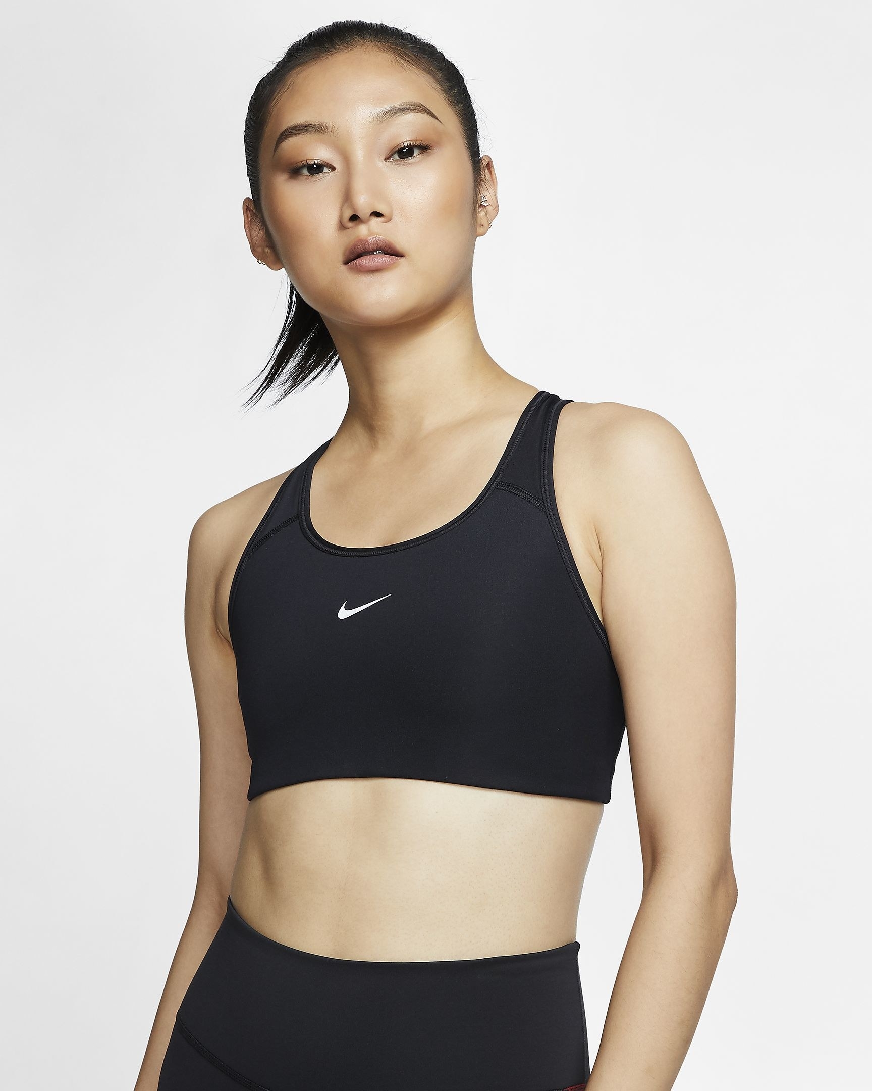 Model wearing black bra with white Nike swoosh in the top center
