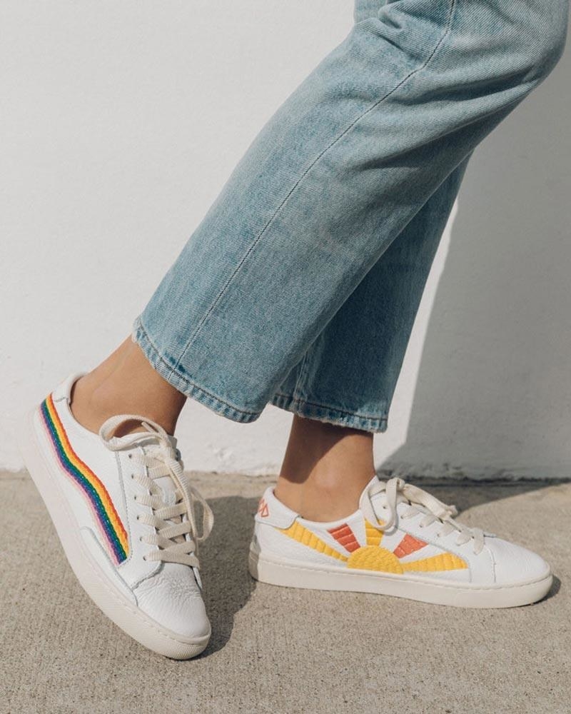 Model wearing the white leather sneakers with a rainbow wave design