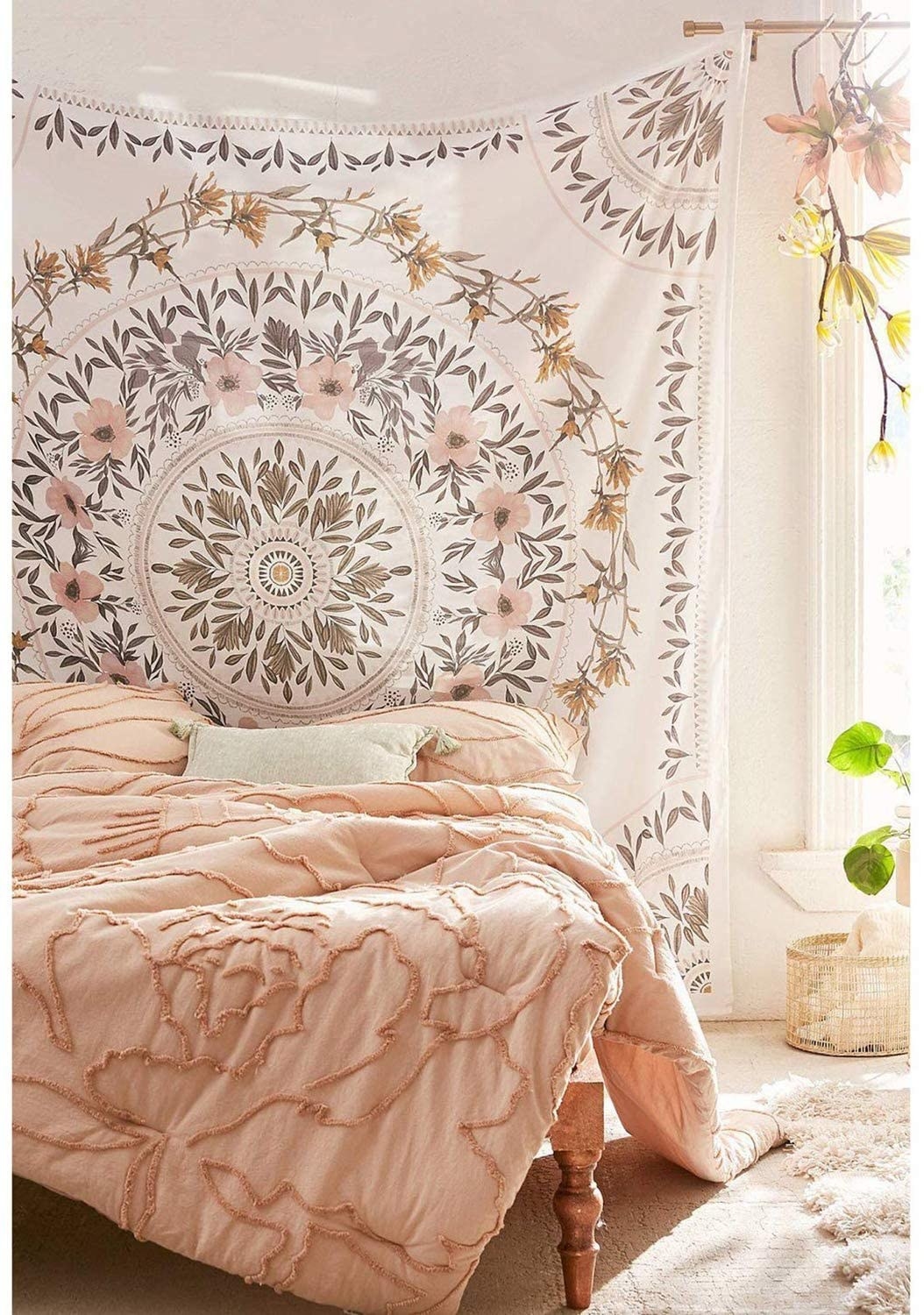 Large white tapestry with pink, green, and brown flowers in leaves in a circular pattern on the tapestry on a wall in a bedroom