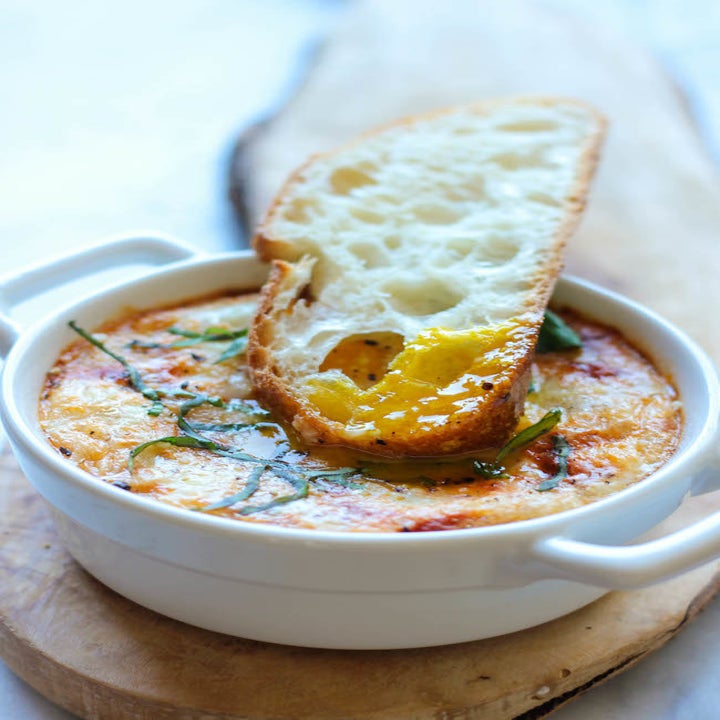 A slice of crusty bread with yolk on it, just dipped into baked eggs.