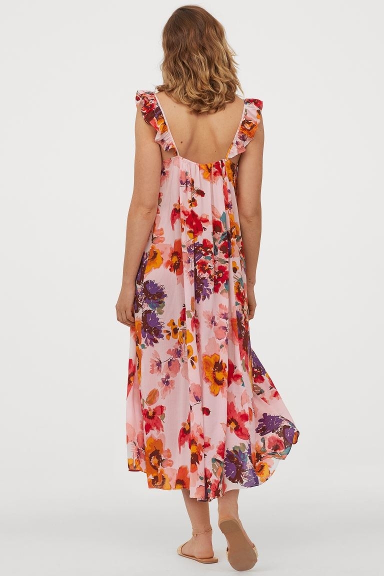 model wearing pink midi dress with orange, purple, and yellow floral design 