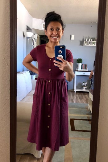 Reviewer taking a mirror selfie in the dress in maroon