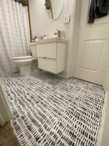 After picture showing the white tiles with black paint-like smudges throughout as tiles on the floor