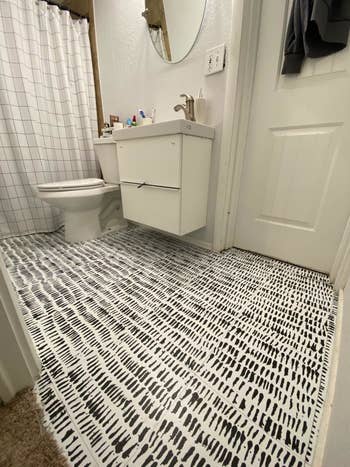 After picture of the bathroom with white tiles with abstract black marks