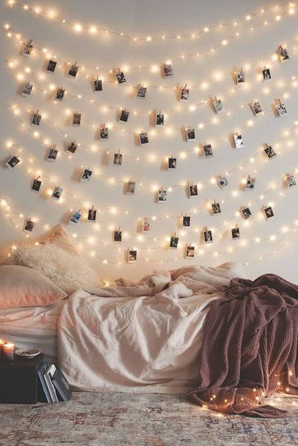 The lights strung up on a wall with Polaroid pictures clipped throughout in a bedroom 