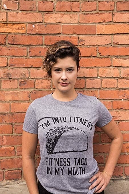 model wearing the shirt that says &quot;I&#x27;m into fitness / fitness taco in my mouth&quot; with a picture of a taco on it