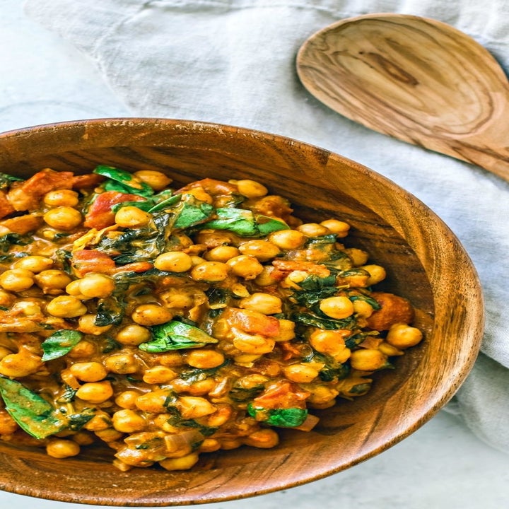A close-up of coconut chickpea curry with spinach in a bowl.