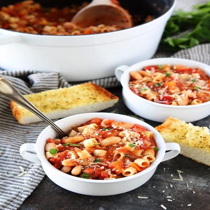 Two bowls of pasta fagioli soup with beans, noodles, and diced tomatoes.