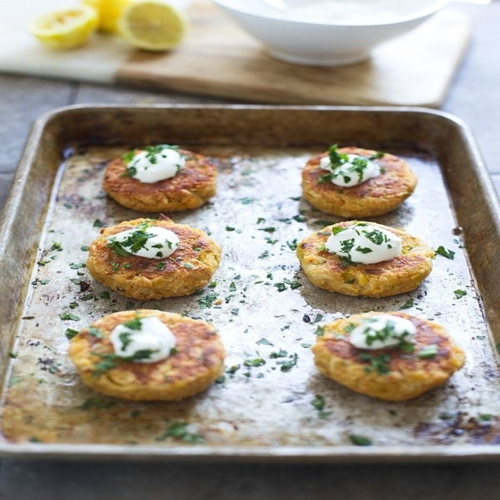 Half a dozen crispy chickpea fritters on a sheet pan with aioli on top.
