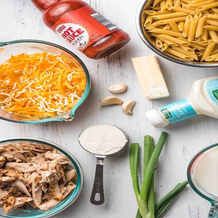 Buffalo sauce, shredded cheese, blue cheese, shredded chicken, pasta, butter, and flour for making buffalo chicken mac 'n' cheese.