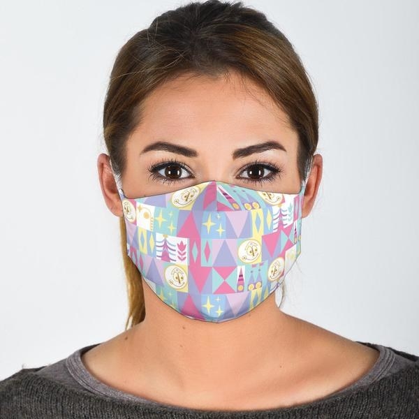 a model wearing a face mask featuring pastel colors designed to look like the it&#x27;s a small world ride