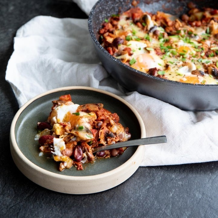 A bowl of baked eggs and beans with stewed tomatoes.