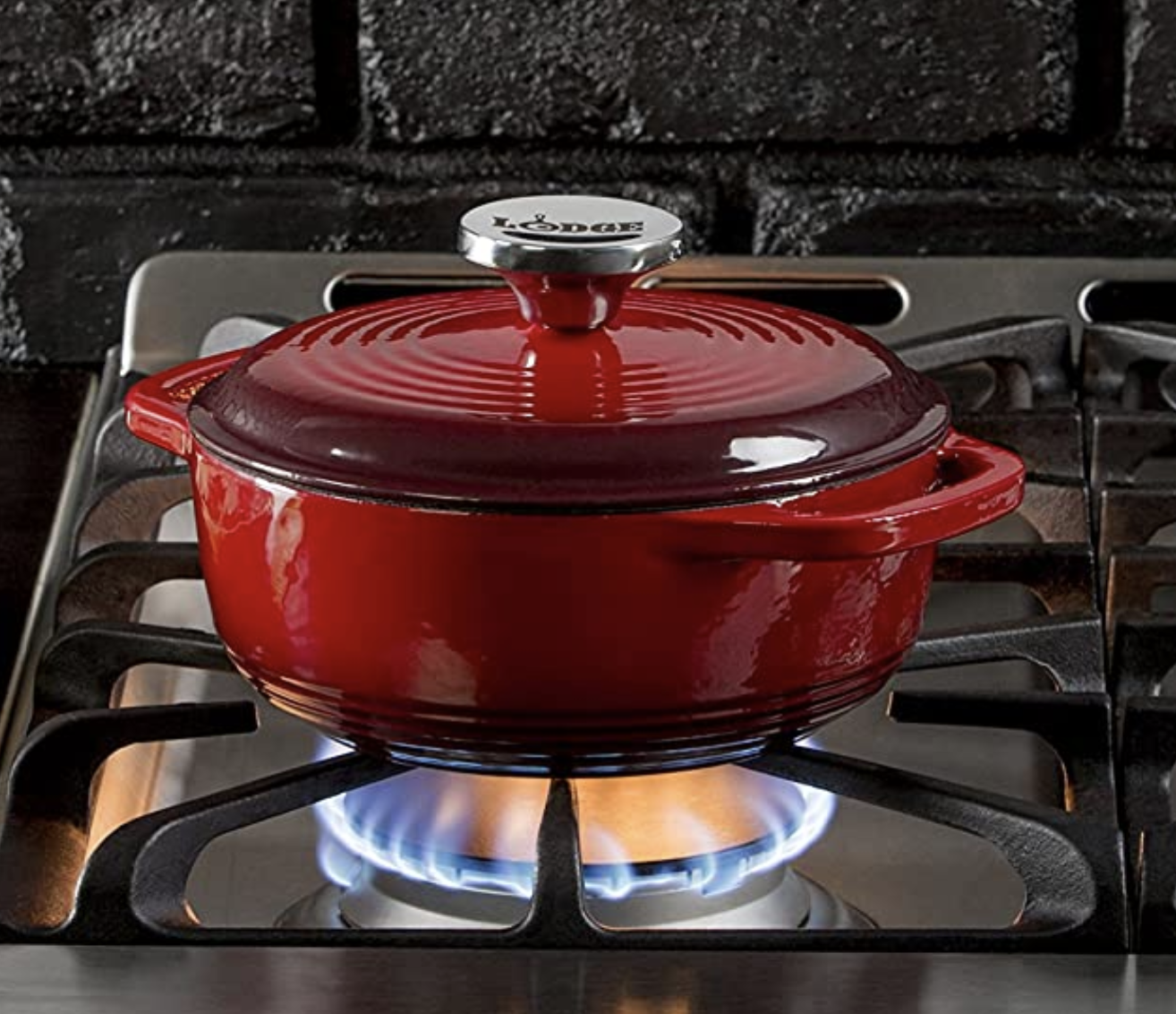 A red ombre dutch oven on a lit stovetop 