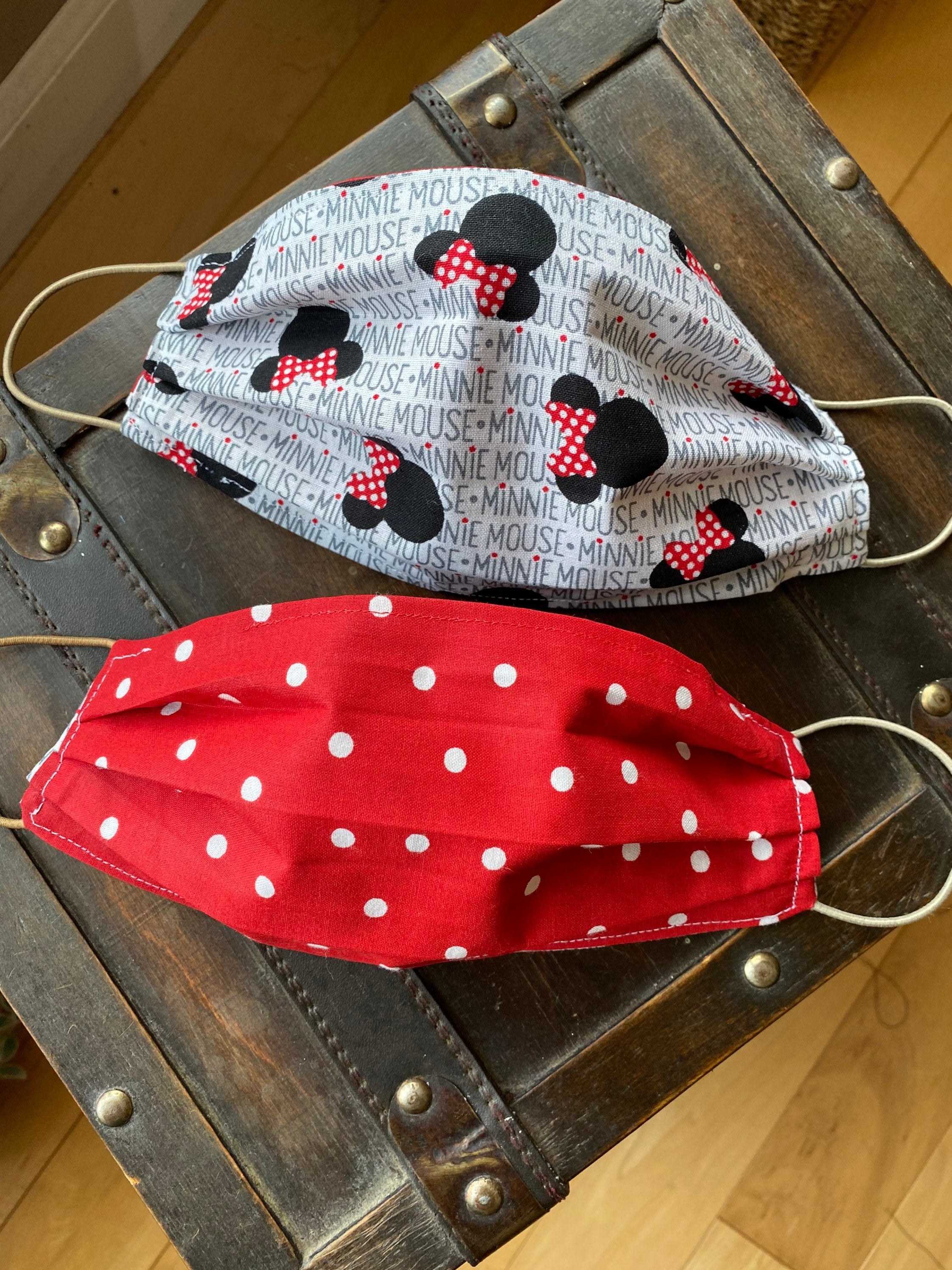 a red mask with white polka dots that reverses into a grey white mask with minnie mouse icons and the written words &quot;minnie mouse&quot; all over it in a pattern