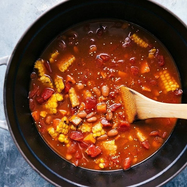 Stirring the chili ingredients: corn, black beans, and spices in diced tomatoes and chicken stock.