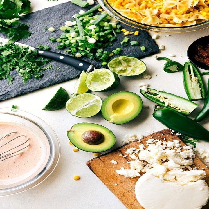 Ingredients for street corn pasta salad including corn kernels, avocado, Cotija cheese, jalapeño, scallion, and lime.