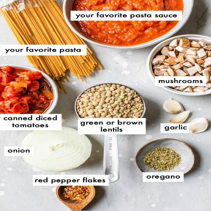 Ingredients for lentil Bolognese, including spaghetti, diced tomatoes, mushrooms, onion, lentils, herbs and spices.