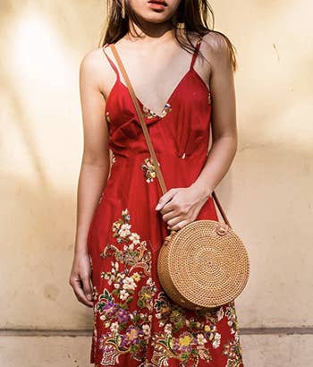 Model wearing a red floral dress with a handwoven circle bag