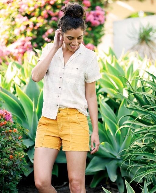 A model wearing the shirt half tucked into shorts