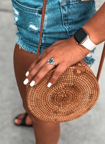 Reviewer wears a handwoven circle bag with high-waisted shorts and sandals
