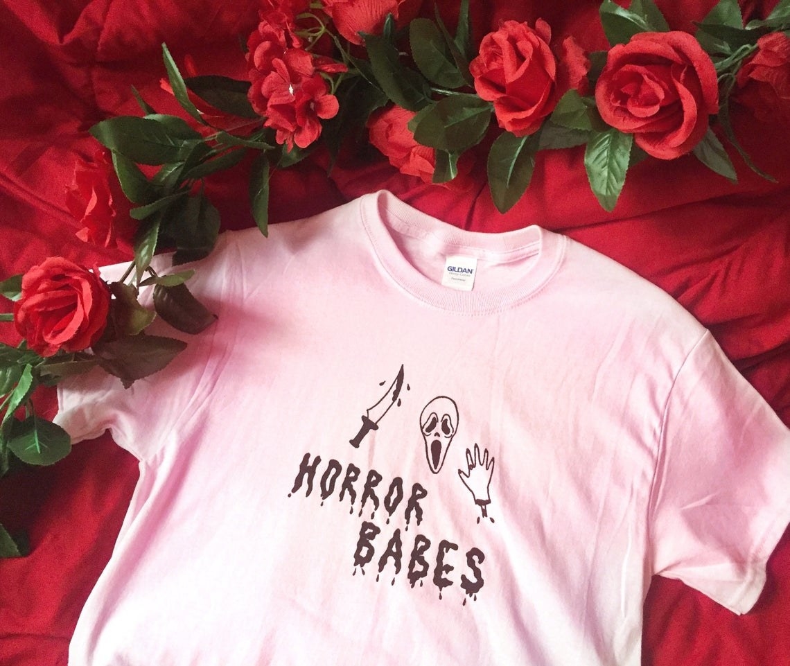 light pink shirt with &quot;horror babes&quot; written on it and illustrations of a Scream movie mask, bloody knife, and hand
