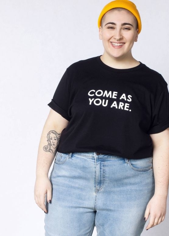 model wearing black shirt with &quot;come as you are&quot; written on it