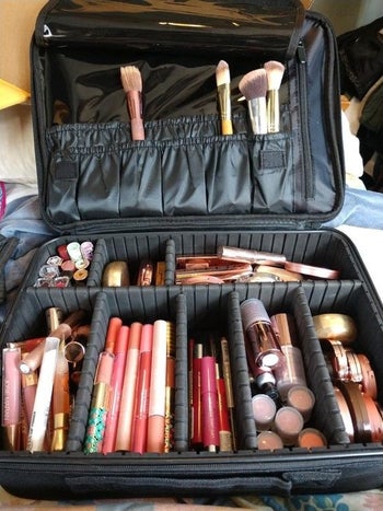Reviewer's image of the open makeup bag to show its adjustable compartments and brush pockets