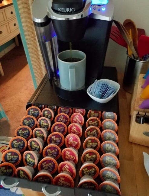 The drawer underneath a Keurig, opened and holding various coffee pods