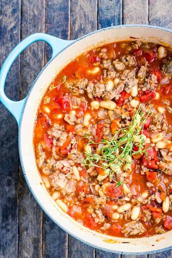 A big Dutch oven full of white bean, tomato, and sausage soup. 
