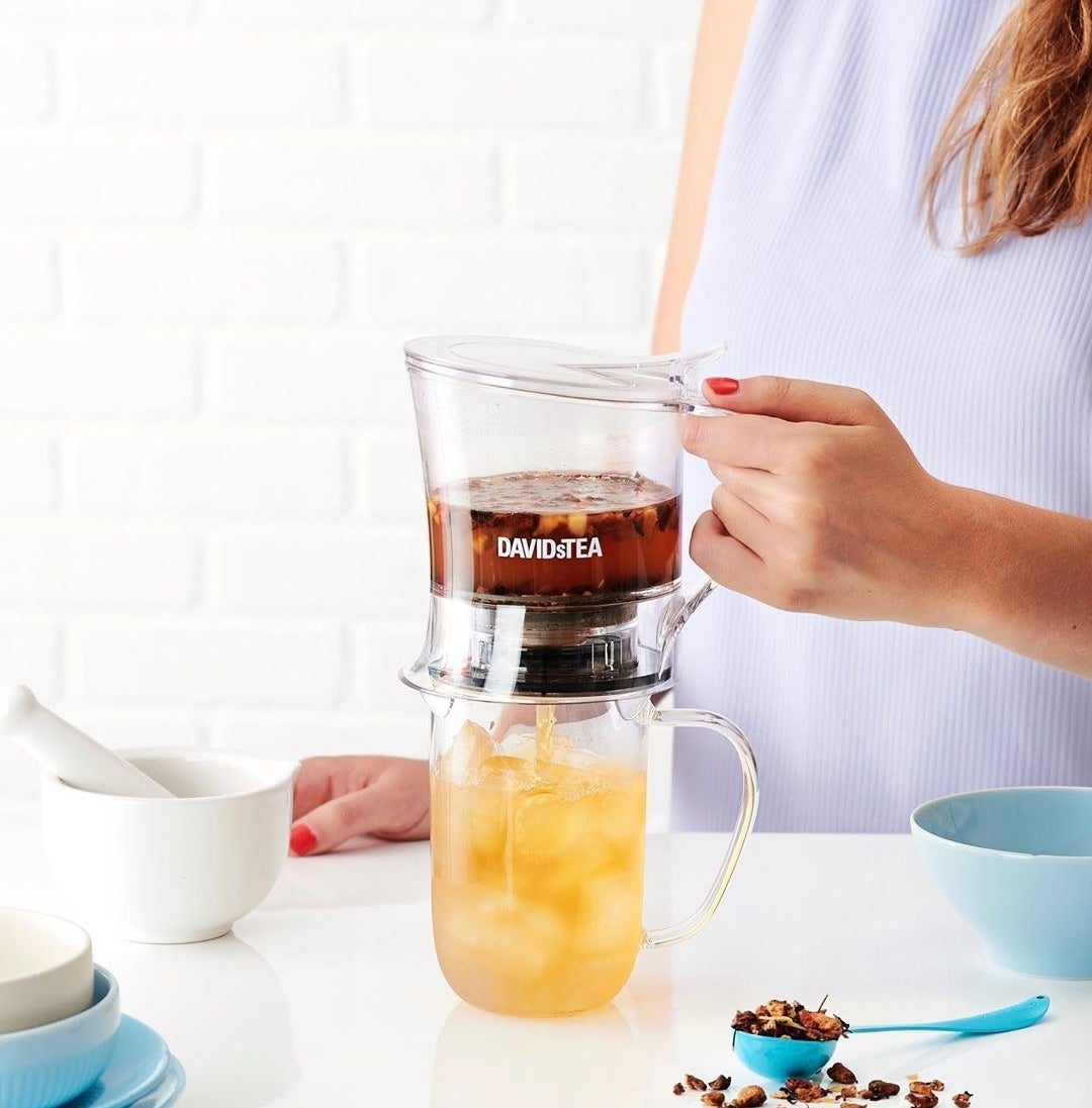 A person using the steeper to make themselves a cup of iced tea