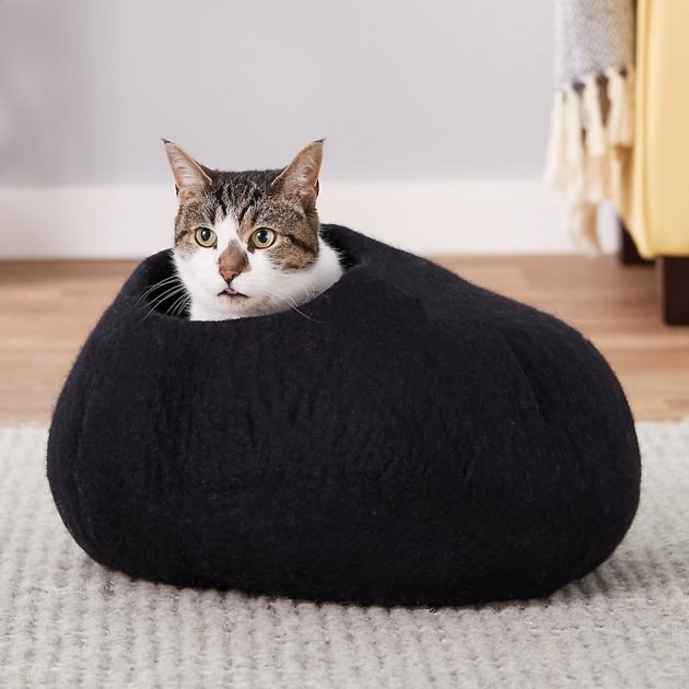 A thick felted wool bed shaped in an oval with a hole on the top