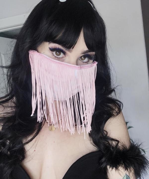 a model wears a pink mask with long tassels 
