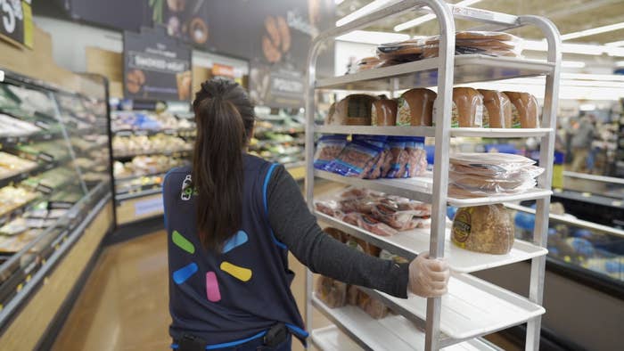 A Walmart employee moving a cart full of meat through the store