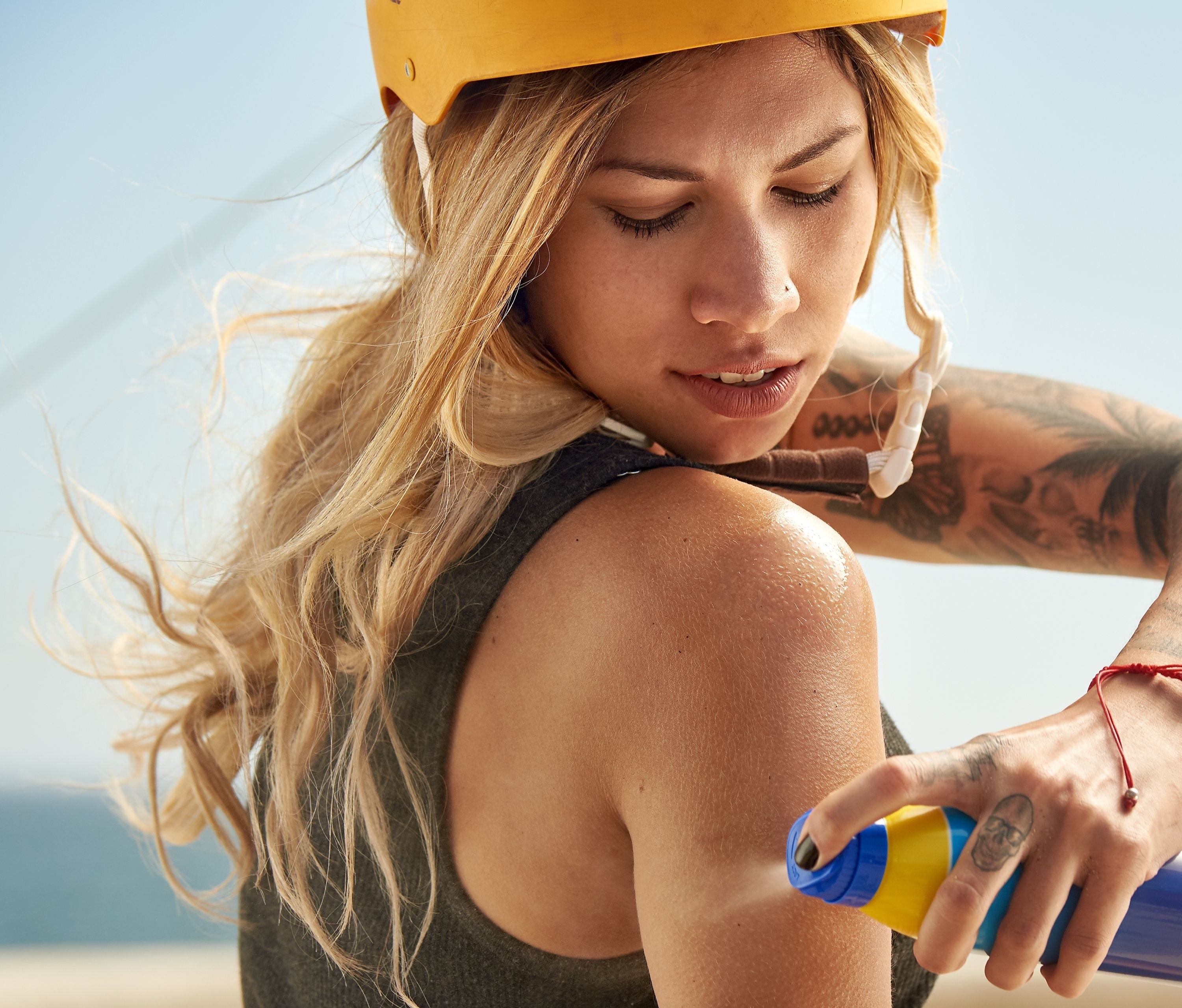 A model applying spray sunscreen to their arm and shoulder