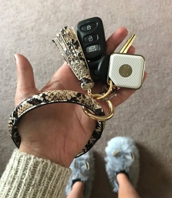 Hand wearing the key ring bracelet in snake print with their keys attached 