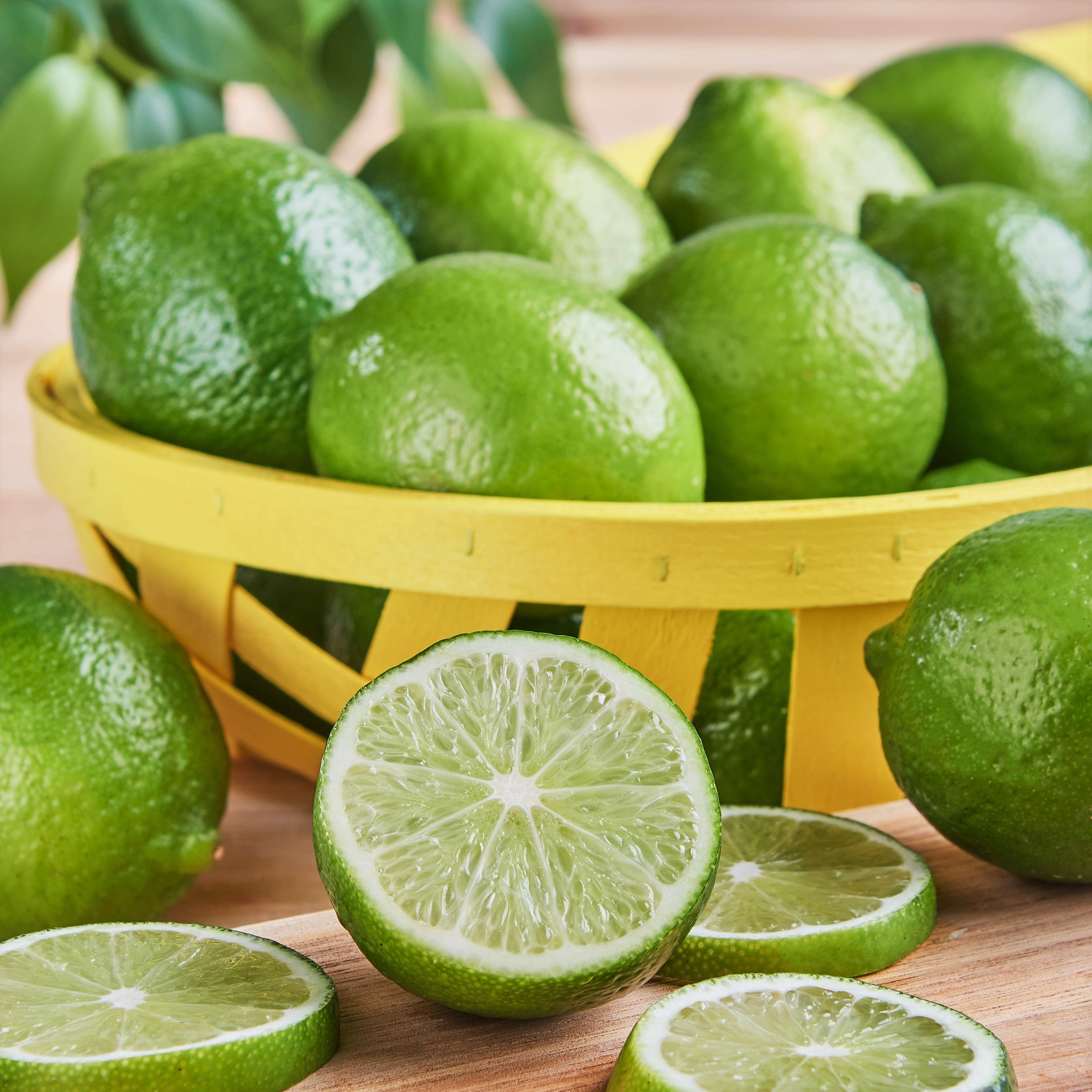 A basket of limes, some sliced open, some cut into slices