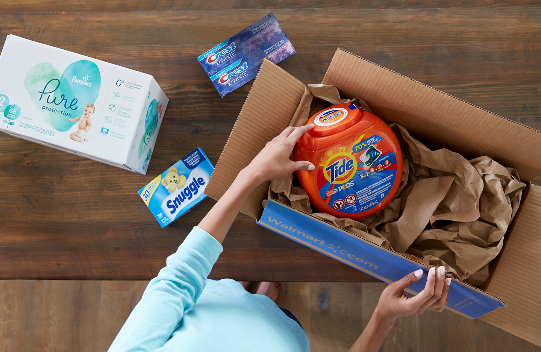A Walmart customer opens a delivery box filled with laundry detergent, dryer sheets, and more household goods