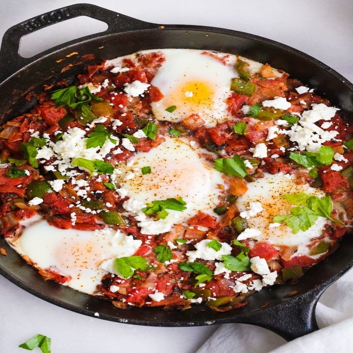 A cast iron skillet with shakshuka, a Middle Eastern dish made with baked eggs in tomato sauce.