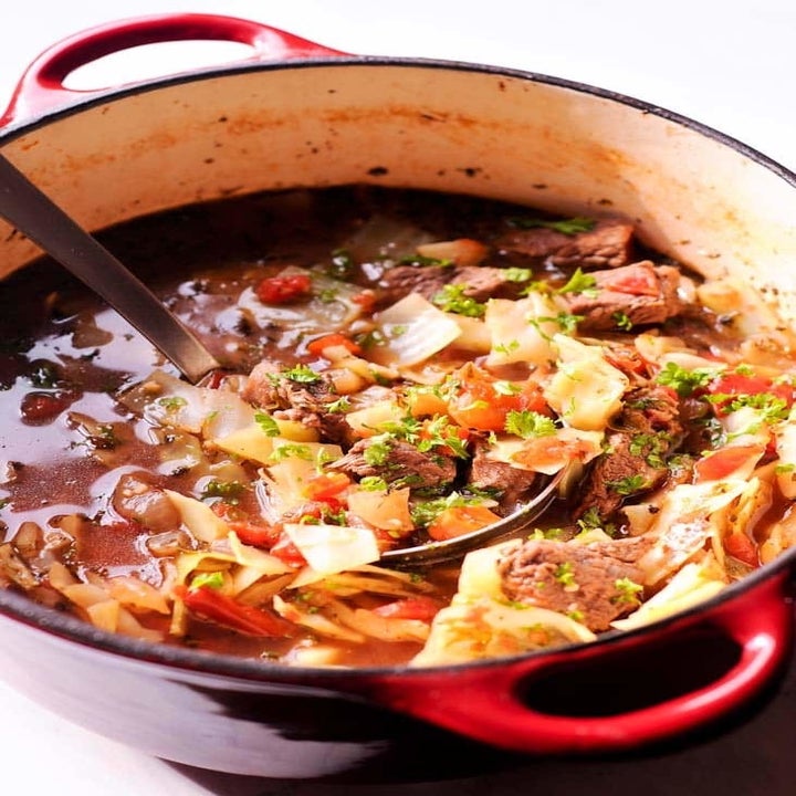 A dutch oven full of beef and cabbage soup.