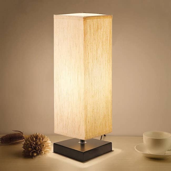 Lamp with square fabric shade in tan and dark brown wood base